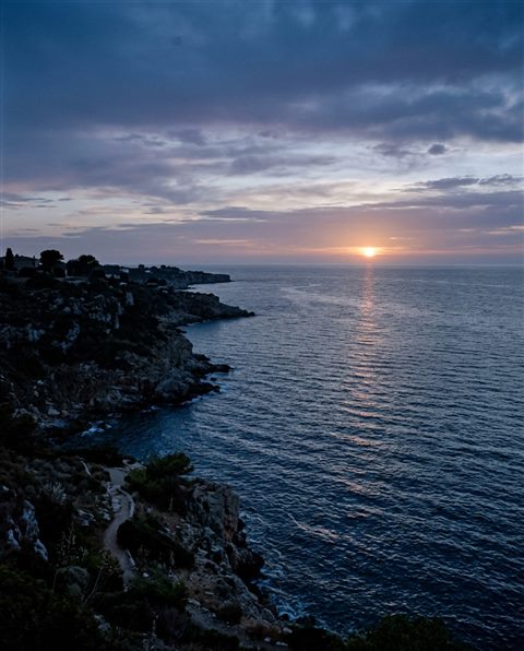 Cinematic film still of sunset over the sea, high-angle view from above, cool blue tones, quiet atmosphere, 4:5 aspect ratio