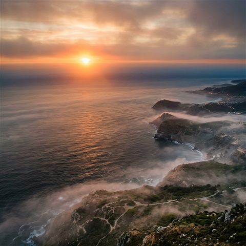 Photorealistic photo of sunset over the sea, high-angle view from above, misty morning haze, dreamy, 1:1 aspect ratio